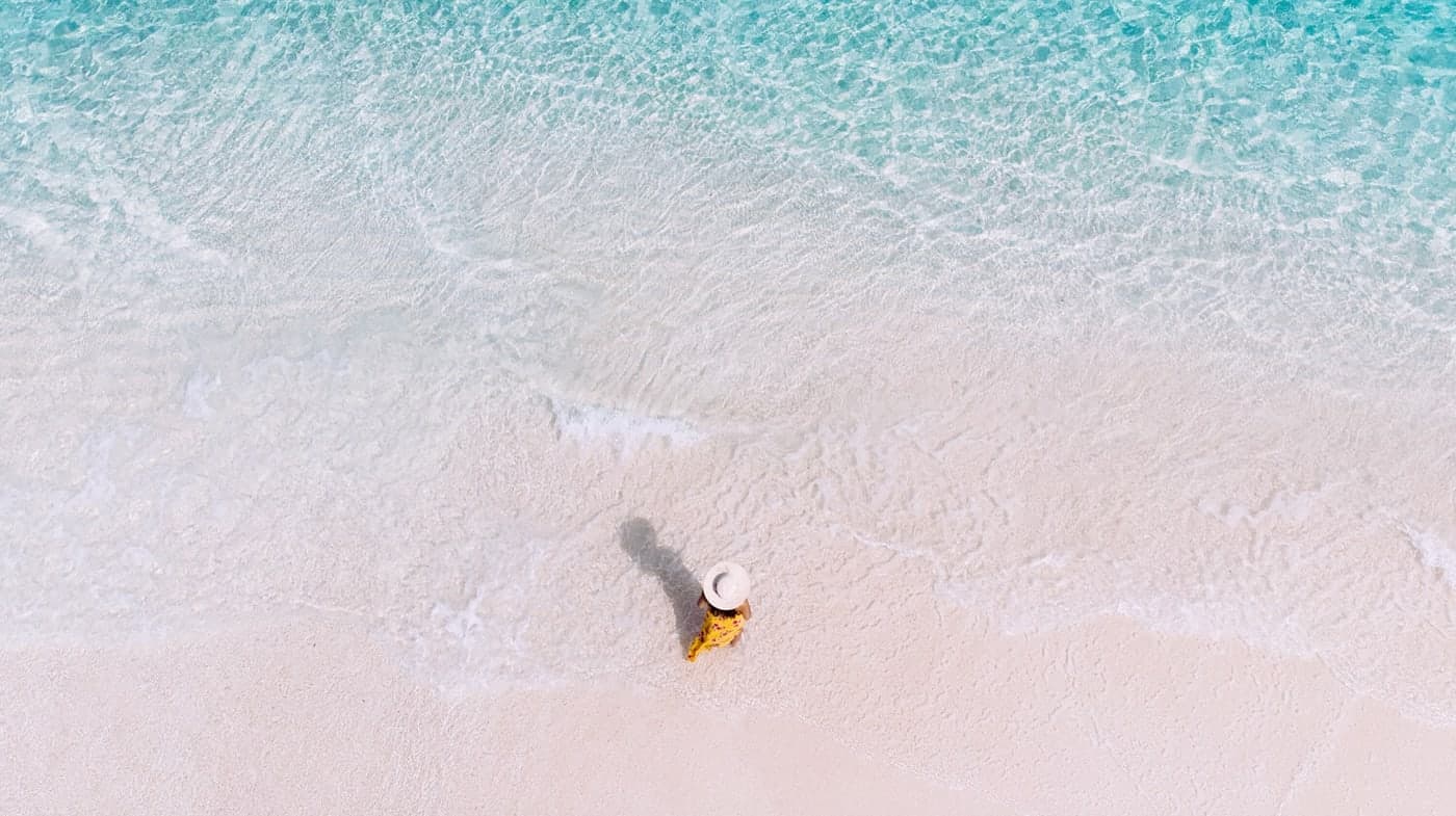 An aerial view of clear turquoise water washing over a Thai beach